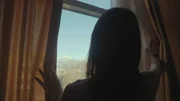 Eine Frau beobachtet ein UFO von ihrem Fenster aus.