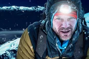 Bergsteiger in winterlicher Outdoor-Kleidung mit Stirnlampe im Schneetreiben. Bergsteiger in winterlicher Outdoor-Kleidung mit Stirnlampe im Schneetreiben.