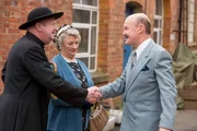 Sir Mortimer (Laurence Kennedy, l.), der Bruder von "Onkel Mirth", begr&uuml;&szlig;t Father Brown (Mark Williams, r.) und Mrs. McCarthy (Sorcha Cusack, M.). Noch ahnen sie nicht, dass der Abend sie in Angst und Schrecken versetzen wird.