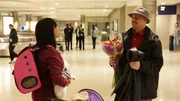 Jasmine holds Coco at the airport while Gino presents her with flowers.