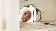 Jasmine Roth examines the wiring inside the home's wall during renovation.