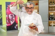 Starkoch Hans J&ouml;rg Bachmeier h&auml;lt einen L&ouml;ffel und ein Tellergericht in der Hand.; Starkoch Hans J&ouml;rg Bachmeier best&auml;ubt einen Teller mit Pfannkuchen.