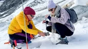 Gletscherforscherin Andrea zeigt Lena, wie sie Schnee untersucht.