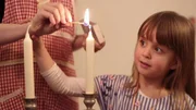 Greta z&uuml;ndet gemeinsam mit ihrer Mutter die Kerzen f&uuml;r den Sabbat an.