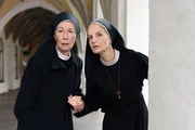 Schwester Felicitas (Karin Gregorek, li.) und Schwester Agnes (Emanuela von Frankenberg) verstecken sich vor Schwester Hanna.