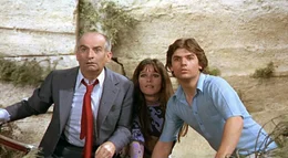 Die Rettung scheint nah: Henri (Louis de Funes, li.) und seine zwei ungebetenen Mitfahrer (Geraldine Chaplin und Olivier de Funes) sind mit dem Auto von der Stra&szlig;e abgekommen und in der Krone einer Pinie gelandet.  +++ Die Verwendung des sendungsbezogenen Materials ist nur mit dem Hinweis und Verlinkung auf RTL+ gestattet. +++