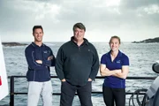 Die Hai-Experten Dr. Charlie Huveneers, Dr. Lauren Meyer und Expeditionsleiter Andrew Fox l&auml;cheln in die Kamera, w&auml;hrend sie vor der K&uuml;ste S&uuml;daustraliens segeln.