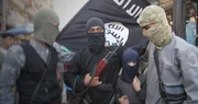 K&auml;mpfer des so genannten Islamischen Staates posieren vor ihrer Fahne.