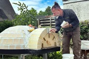 Daniel Reisinger mauert das Eingangsportal des Pizzaofens. Zum Mauern benutzt der Ofenbauer feuerfesten M&ouml;rtel.