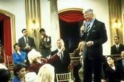 Winston (Barry Bostwick, r. stehend) handelt auf der alljährlichen Junggesellenversteigerung mit einer älteren Dame. Winston (Barry Bostwick, r. stehend) handelt auf der alljährlichen Junggesellenversteigerung mit einer älteren Dame.