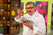 Starkoch Hans J&ouml;rg Bachmeier steht in der Studiok&uuml;che. Er hat einen Teller in der Hand und probiert das Gericht.