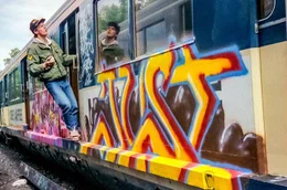 Justus 1987 beim Spr&uuml;hen seines Just S-Bahn-Panels im Yard Bergedorf. Um etwas h&ouml;her zu spr&uuml;hen, konnte man sich wie beim S-Bahn-Surfen auf den Vorsprung an der Bahn stellen und sich an der offenen T&uuml;r oder der Regenrinne festhalten.
