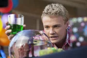Cam (Dominic Deutscher) schaut ungläubig in das Goldfischglas. Wie kann es sein, dass Evie dort als Mini-Meerjungfrau herumschwimmt? Cam (Dominic Deutscher) schaut ungläubig in das Goldfischglas. Wie kann es sein, dass Evie dort als Mini-Meerjungfrau herumschwimmt?
