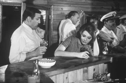 Am Abend vor dem Abflug: Rae (Sylvia Koscina) und Jacques (Lino Ventura, li.) nehmen einen Drink in einer Bar.