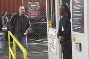 Broadsky (Arnold Vosloo, li.) hat dem Toten eine Zugangskarte f&uuml;r das Hafengebiet entwendet und der W&auml;chter (Arnold D. Charity) l&auml;sst ihn passieren. Die Verwendung des sendungsbezogenen Materials ist nur mit dem Hinweis und Verlinkung auf TVNOW gestattet.