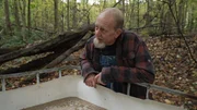 Eric "Digger" Manes standing over a tote full of mash at the still site in the woods.