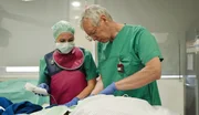 Ein Arzt und eine Pflegekraft arbeiten hochkonzentriert am Patienten.