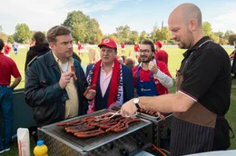 Die Fans von Rot-Wei&szlig; Niederkaltenkirchen stehen Schlange, um bei Metzger Simmerl (Stephan Zinner, re.) eine Wurst zu ergattern: Dorfpolizist Franz Eberhofer (Sebastian Bezzel, li.), der B&uuml;rgermeister (Thomas K&uuml;gel, 2. v. li.) und Heizungspfuscher Fl&ouml;tzinger (Daniel Christensen, 2. v. re.)