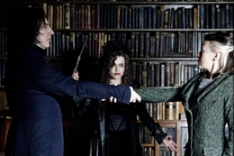 L-R: Professor Severus Snape (Alan Rickman)  grabbing arm of Narcissa Malfoy (Helen McCrory)  , withBellatrix LeStrange (Helena Bonham Carter)  standing aside, looking on.