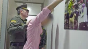 The official pats down the suspect to verify that he isn't carrying any substances on his body. The official pats down the suspect to verify that he isn't carrying any substances on his body.