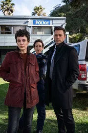 Detective Senior Sergeant Jessica Savage (Kate Elliott, l.), ihr Kollege Detective Sergeant Justin Harding (Ido Drent, r.) und Senior Sergeant Denise Abernethy (Alison Bruce, M.) stehen in Nahaufnahme vor der Polizeistation in Waiheke. In dieser Folge wird die Freundin von Denise bedroht und der Erpresser von Jess wird enttarnt. Detective Senior Sergeant Jessica Savage (Kate Elliott, l.), ihr Kollege Detective Sergeant Justin Harding (Ido Drent, r.) und Senior Sergeant Denise Abernethy (Alison Bruce, M.) stehen in Nahaufnahme vor der Polizeistation in Waiheke. In dieser Folge wird die Freundin von Denise bedroht und der Erpresser von Jess wird enttarnt.