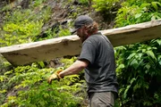 Scott Allen trägt eine Holzplanke. Scott Allen trägt eine Holzplanke.