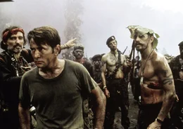Captain Willard (Martin Sheen, 2. v. li.) ist zusammen mit Jay Hicks (Frederic Forrest, re.) in der H&ouml;lle von Colonel Kurtz angekommen, wo er von einem &uuml;berdrehten amerikanischen Fotoreporter (Dennis Hopper, li.) in Empfang genommen wird.