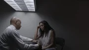 A detective talks to a woman in an interrogation room.