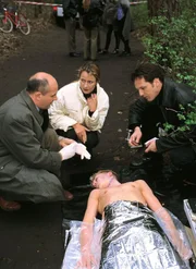 Die Leiche eines Jungen (Komparse, lieg.) ist gefunden worden. Der Gerichtsmediziner (Klaus Schindler, li.) spricht mit der Staatsanwältin (Britta Schmeling) und Ralf Bongartz (Max Gertsch) über eine mögliche Todesursache. Die Leiche eines Jungen (Komparse, lieg.) ist gefunden worden. Der Gerichtsmediziner (Klaus Schindler, li.) spricht mit der Staatsanwältin (Britta Schmeling) und Ralf Bongartz (Max Gertsch) über eine mögliche Todesursache.