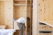 Kleiderschrank aus Zirbenholz: Schreiner Julius Lux beim Aufbau des Schranks in der Wohnung der Kundin in Stuttgart &ndash; Anbringung der Glast&uuml;ren.