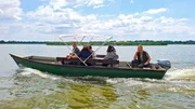 Martina und ihre Familie (v.l.n.r.: Vater J&aacute;nos, Mutter Anita, j&uuml;ngerer Bruder B&aacute;lint) und ihr Gro&szlig;vater (Fischer J&aacute;nos am Motor/Steuer) auf einer Bootstour zum Thei&szlig;-See. Alle drei Generationen genie&szlig;en die Landschaft. Politische Themen werden vermieden, obwohl sie an Pl&auml;tzen vorbeifahren, wo die Fidesz-Korruption offensichtlich stattfand.