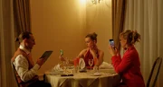 Familie Sommer sitzt in Abendgarderobe an einem Tisch in einem gehobenen Restaurant. Von links: Chris (Liliom Lewald), Luca (Maja Bons) und Stella (Bea Brocks) Familie Sommer sitzt in Abendgarderobe an einem Tisch in einem gehobenen Restaurant. Von links: Chris (Liliom Lewald), Luca (Maja Bons) und Stella (Bea Brocks)