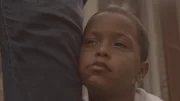 Young Demery's face leans against a grown-up leg.
