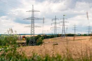 Hilfe aus der Luft: Hubschrauber im Einsatz beim Hochleitungsbau. Ein Hubschrauber zieht das gelbe Vorseil auf die Masten.