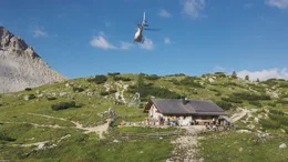 Warentransport mit dem Hubschrauber. Pilot Hansi Tschurtschentaler fliegt eine H&uuml;tte unterhalb der Drei Zinnen an.