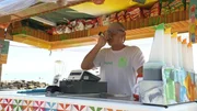 This image shows a person working behind a beachside drink and snack bar counter This image shows a person working behind a beachside drink and snack bar counter