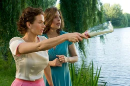 v.li.: Susanne (Melika Foroutan) wirft die Flaschenpost unter Viviens (Elena Uhlig) Jubel in den Fluss.