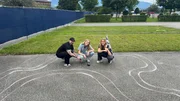 Lisa und Stefan legen Lena rein: Sie denkt, sie soll ihn mit dem Spielzeugauto auf einer aufgemalten Rennstrecke besiegen.