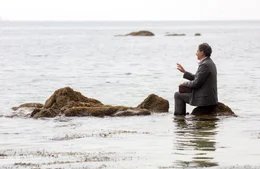 Charles (Denis Podalyd&egrave;s) sitzt auf einem Stein im Meer.