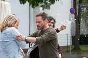 Rosa Schmelke (Katrin Wichmann) gerät in eine eskalierende Situation, als Leo Oswald (Wanja Mues, Mi.) eingreift und sie schützt. Hinter ihnen attackiert David Rudolf (Samy Challah, r.) die Szene – ein Moment, der die angespannte Dynamik des Falls offenlegt. Rosa Schmelke (Katrin Wichmann) gerät in eine eskalierende Situation, als Leo Oswald (Wanja Mues, Mi.) eingreift und sie schützt. Hinter ihnen attackiert David Rudolf (Samy Challah, r.) die Szene – ein Moment, der die angespannte Dynamik des Falls offenlegt.