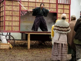 Tornados Vater Fujin (Takehiro Hira) unterh&auml;lt die Menge mit einem St&uuml;ck &uuml;ber zwei Samurai.