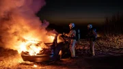 Auf dem nächtlichen Sandstrand von De Haan brennt ein Auto, in dessen Kofferraum die Feuerwehr (Komparsen) eine verkohlte Leiche findet. Auf dem nächtlichen Sandstrand von De Haan brennt ein Auto, in dessen Kofferraum die Feuerwehr (Komparsen) eine verkohlte Leiche findet.
