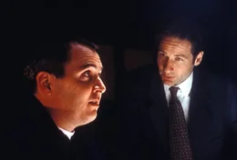 Eddie van Blundht (Darin Morgan, l.) wird von Mulder (David Duchovny, r.) verd&auml;chtigt, ohne Wissen der betreffenden M&uuml;tter der Vater von f&uuml;nf Babys mit rudiment&auml;ren Schw&auml;nzen zu sein.