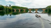 Patrick Cechetto in seinem Boot – einer der letzten Berufsfischer auf der Dordogne vor einer Bogenbrücke im Hintergrund. Patrick Cechetto in seinem Boot – einer der letzten Berufsfischer auf der Dordogne vor einer Bogenbrücke im Hintergrund.