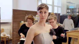 Der Film begleitet S&auml;ngerinnen und S&auml;nger, Chor, G&uuml;rzenich-Orchester, Kost&uuml;m, B&uuml;hnenbild und B&uuml;hnentechnik. Sie erz&auml;hlt von Erinnerungen, Hoffnungen und Entt&auml;uschungen &ndash; und von der Frage, was ein Ort mit den Menschen macht, die dort arbeiten. Richard Strauss' &bdquo;Der Rosenkavalier&ldquo; ist die erste Premiere im neuen alten Haus. Pl&ouml;tzlich geht es nicht mehr um die Baustelle, sondern darum, wie dieser Ort wieder zum Leben erwacht. Bianca Andrew, Mezzosopranistin, bei der Anprobe.