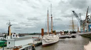 Versteckt im Hanshafen, unter der Plane. Vor 100 Jahren brachte der Lotsenschoner noch die Lotsen an Bord auf die Viermastbark PEKING, im Hintergrund Versteckt im Hanshafen, unter der Plane. Vor 100 Jahren brachte der Lotsenschoner noch die Lotsen an Bord auf die Viermastbark PEKING, im Hintergrund