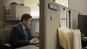 Contributor Thien Do, Lead investigator, sat at his desk looking at his laptop in front of him. There is a an office cubicle divider in front of him, with a computer, stack of paperwork and water bottle on the other side of it, out of focus. Interior, landscape