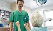 Ein Lächeln im Klinikalltag: Ein Pfleger und eine ältere Patientin teilen einen heiteren Moment. Ein Lächeln im Klinikalltag: Ein Pfleger und eine ältere Patientin teilen einen heiteren Moment.