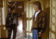 Der Drogenh&auml;ndler Spider (Ramon Franco, l.) bedroht MacGyver (Richard Dean Anderson, r.) mit einer Waffe.