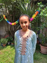 Basma steht im geschmückten Garten. Sie hat ihr großes Nachbarschaftsessen vorbereitet und freut sich auf das Fest. Die bunten Girlanden spiegeln die Vielfalt wider, die sie zusammenbringen möchte. Basma steht im geschmückten Garten. Sie hat ihr großes Nachbarschaftsessen vorbereitet und freut sich auf das Fest. Die bunten Girlanden spiegeln die Vielfalt wider, die sie zusammenbringen möchte.